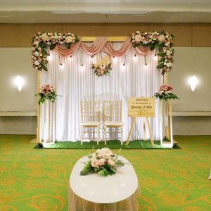 Backdrop pelaminan pernikahan ballroom indoor kain draping pink putih bunga segar kursi Tiffany gold